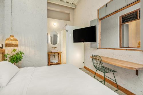 a bedroom with a white bed and a chair at Botánica Casa Hotel Manila by HOUSY HOST in Medellín