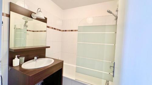 une salle de bain avec un lavabo et une douche en verre dans l'établissement Logement lumineux 10min Disney, à Montévrain