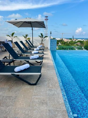 a row of lounge chairs next to a swimming pool at Areia Boutique Hotel - Puerto Morelos in Puerto Morelos