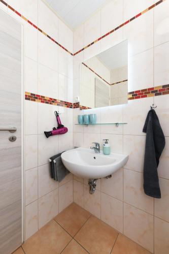 a bathroom with a sink and a mirror at Ferienwohnungen Haus Boje in Neuharlingersiel