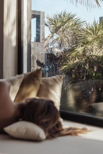 a woman laying on a couch looking out a window at UMi Tulum in Tulum