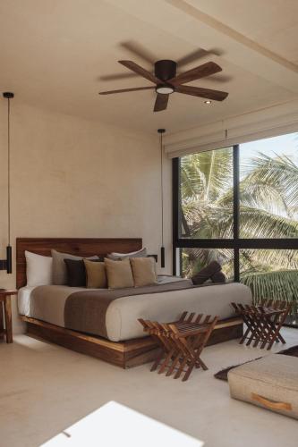a bedroom with a large bed with a ceiling fan at UMi Tulum in Tulum