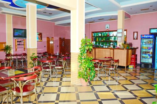 a restaurant with pink walls and tables and chairs at Hotel Gjeli in Fier