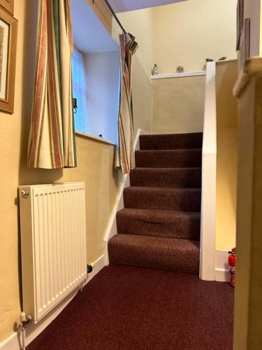 a staircase in a house with brown carpet at Llanidloes Townhouse-pet-friendly-sleeps 7-Mid Wales in Llanidloes