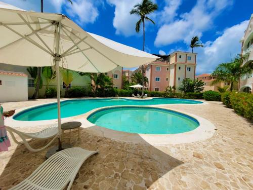 プンタ・カナにあるEl Dorado Condo 210Aのパラソルと椅子付きのスイミングプール