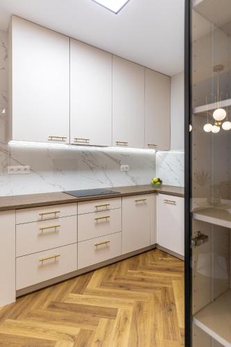 a kitchen with white cabinets and a wooden floor at AH Luxury Designer Aparment Bastova in Košice