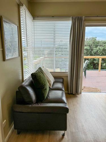a leather couch in a living room with a large window at Hennessy Beach House in Port Campbell
