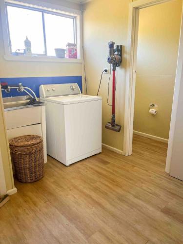 a laundry room with a washing machine and a window at Hennessy Beach House in Port Campbell
