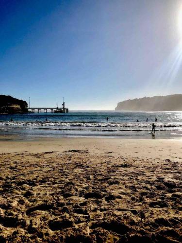 a beach with people in the water and a pier at Hennessy Beach House in Port Campbell