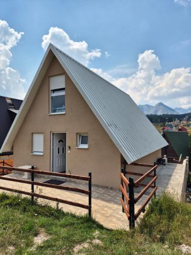 a house with a pitched roof and a fence at Guest House Tamara in Žabljak