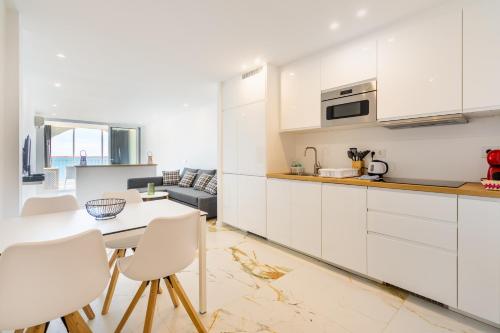 a kitchen with white cabinets and a table and chairs at Apartamento Frente del Mar in Empuriabrava
