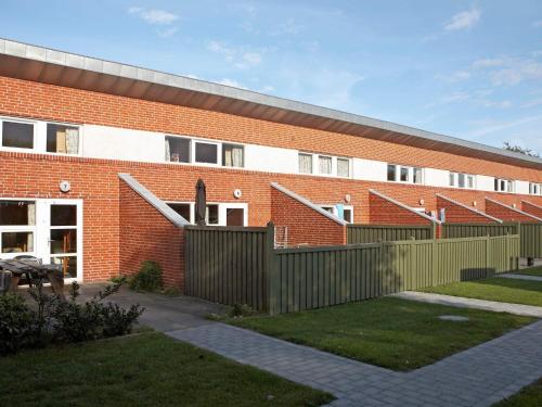 a brick building with a fence in front of it at 6 person holiday home on a holiday park in Hemmet in Hemmet