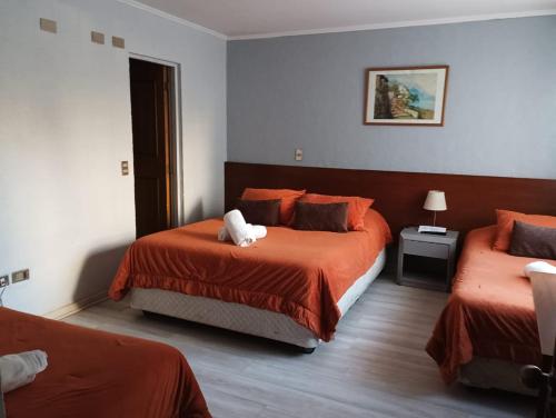 a hotel room with two beds with orange sheets at Hotel 5 Norte in Viña del Mar
