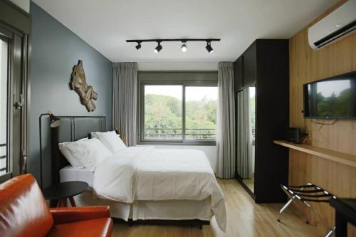 a bedroom with a white bed and a window at Apto frente parque com vista e piscina in Porto Alegre