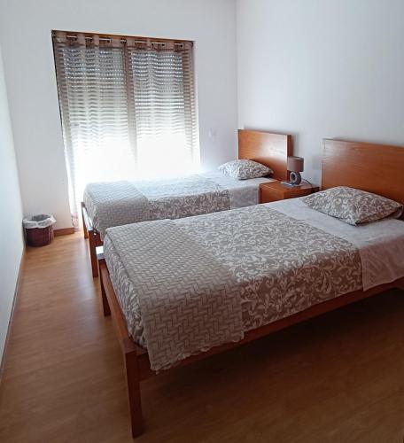 a bedroom with two beds and a window at Portela - APARTAMENTO in Viana do Castelo
