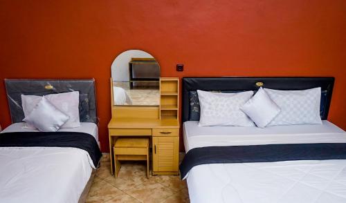a bedroom with two beds and a desk with a mirror at New Bintang By Four-G in Bajawa