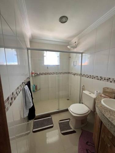 a bathroom with a shower and a toilet and a sink at Casa com piscina, churrasqueira e ar condicionado em condomínio in Cabo Frio