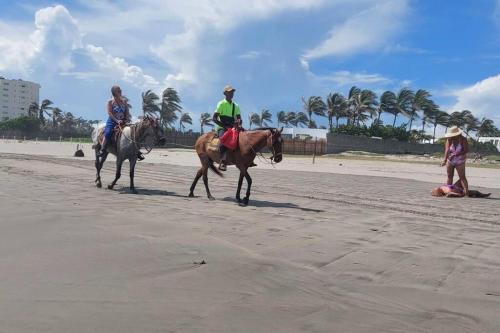 two people are riding horses on the beach at Bonito departamento planta baja en zona diamante in Barra Vieja
