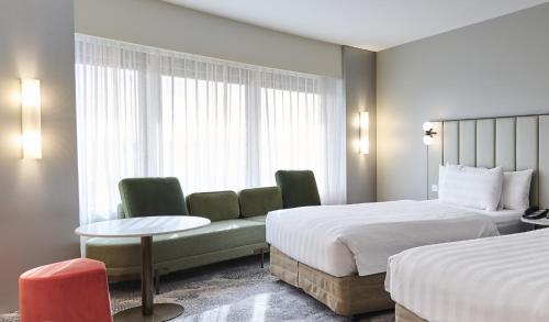 a hotel room with two beds and a couch at PARKROYAL Melbourne Airport in Melbourne