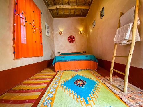 a bedroom with a bed and a rug on the floor at Auberge Ayouze in Aït Ben Haddou