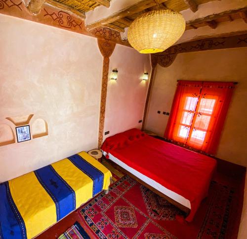 two beds in a room with a window at Auberge Ayouze in Aït Ben Haddou