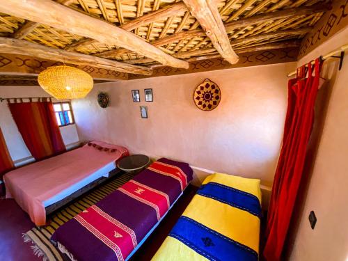 a room with two beds and a table in it at Auberge Ayouze in Aït Ben Haddou