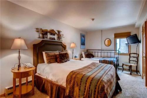a hotel room with a large bed and a television at Ski In, Ski Out 2 Bedroom Vacation Rental In The Heart Of Lionshead Village With Heated Slope Side Pool And Hot Tub in Vail