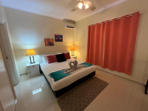 a bedroom with a bed and a red curtain at Tranquil Eagle Beach Condo, sleeps 4 to 6 in Palm-Eagle Beach