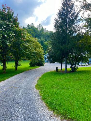a gravel road with trees and a house in the distance at Firefly Fields 2-Acres With Guest House, Game Room, Mountain & River Views in Sevierville