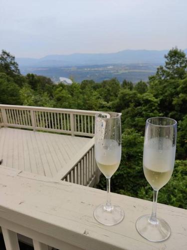 two glasses of white wine sitting on a table on a balcony at Paradise View Cabin on Massanutten Mountain in Luray