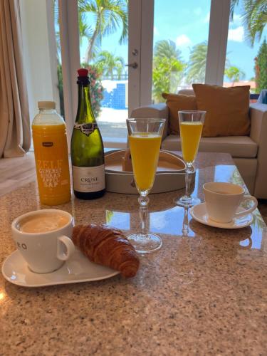 a table with a breakfast of coffee and croissants and drinks at Tranquil Eagle Beach Condo, sleeps 4 to 6 in Palm-Eagle Beach