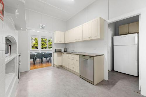 a kitchen with white cabinets and a white refrigerator at The Seamist Cottage in Narooma