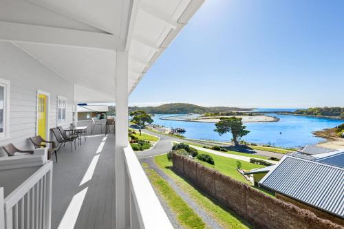 a house with a balcony with a view of the water at The Seamist Cottage in Narooma