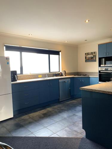 a kitchen with blue cabinets and a large window at Haast River Motels & Holiday Park in Haast