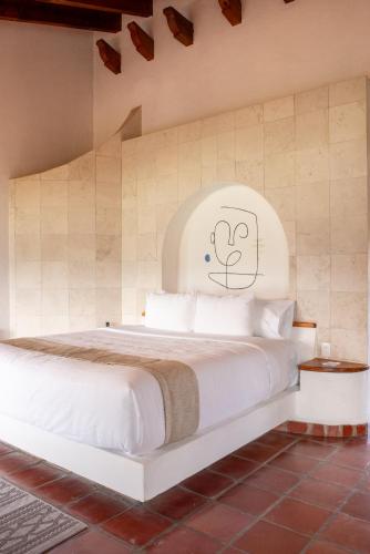 a bedroom with a white bed with a face drawn on the wall at Hanna Hotel Boutique in Valle de Bravo