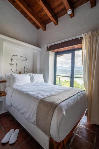 a bedroom with a large bed with a large window at Hanna Hotel Boutique in Valle de Bravo