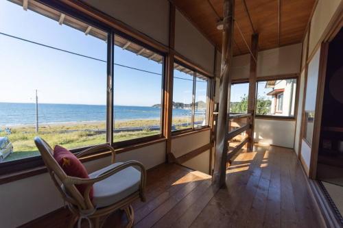 a room with a chair and a view of the ocean at 砂浜まで10秒 海と桟橋を一望できるHaraoka House in Minamiboso