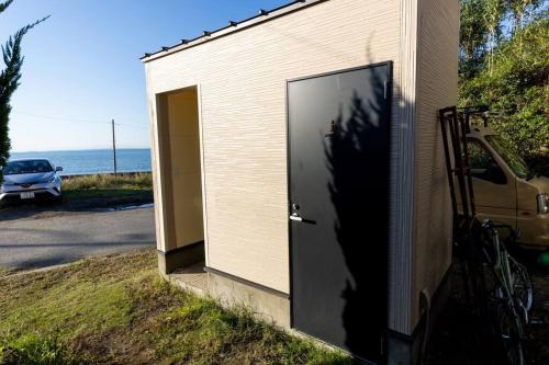 a door on the side of a building with a car at 砂浜まで10秒 海と桟橋を一望できるHaraoka House in Minamiboso