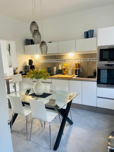 une cuisine avec une table en verre et des placards blancs dans l'établissement Maison 