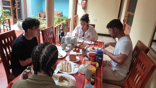 a group of people sitting around a table eating food at Kisanga Homestay in Moshi