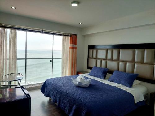 a bedroom with a blue bed with a large window at Hotel Riviera Muchik in Huanchaco