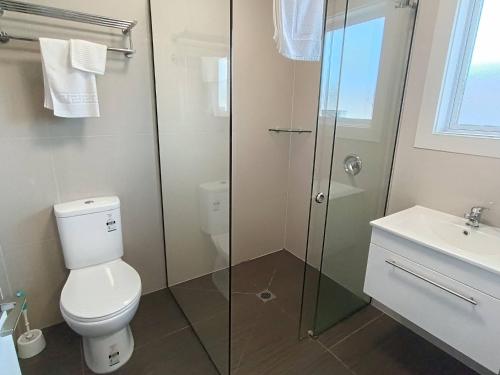 a bathroom with a toilet and a glass shower at Bayfield Motel and Apartment in Dunedin