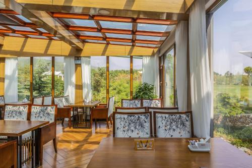 a dining room with tables and chairs and large windows at Dengfeng Zhongzhou Huading Hotel in Dengfeng