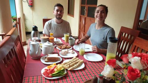 a man and woman sitting at a table with food at Kisanga Homestay in Moshi