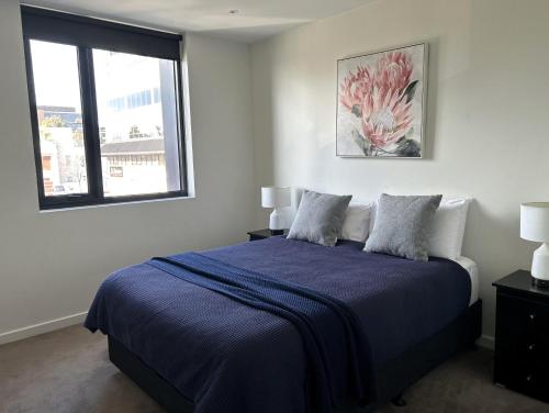a bedroom with a bed with a blue blanket and a window at PIER POINT 3 Bedroom Apartment with Bay Views on the Geelong Waterfront - 801 in Geelong