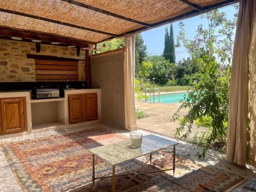 d'une terrasse avec une table et une vue sur la piscine. dans l'établissement La Bergerie du figuier, à Céret