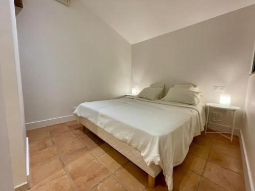 a bedroom with a white bed with two lamps on it at La Bergerie du figuier in Céret