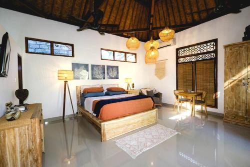 ein Schlafzimmer mit einem Bett, einem Schreibtisch und einem Stuhl in der Unterkunft Indah puri Bali Bungalow on Candidasa beach in Candidasa
