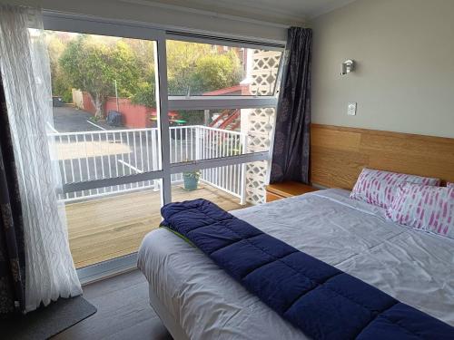 a bedroom with a bed and a large window at Bayfield Motel and Apartment in Dunedin