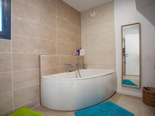 La salle de bains est pourvue d'une baignoire blanche et d'un miroir. dans l'établissement Villa Spacieuse avec Spa - Calme et Proche Plage, Lac et Golfs - FR-1-791-3, à Soorts-Hossegor